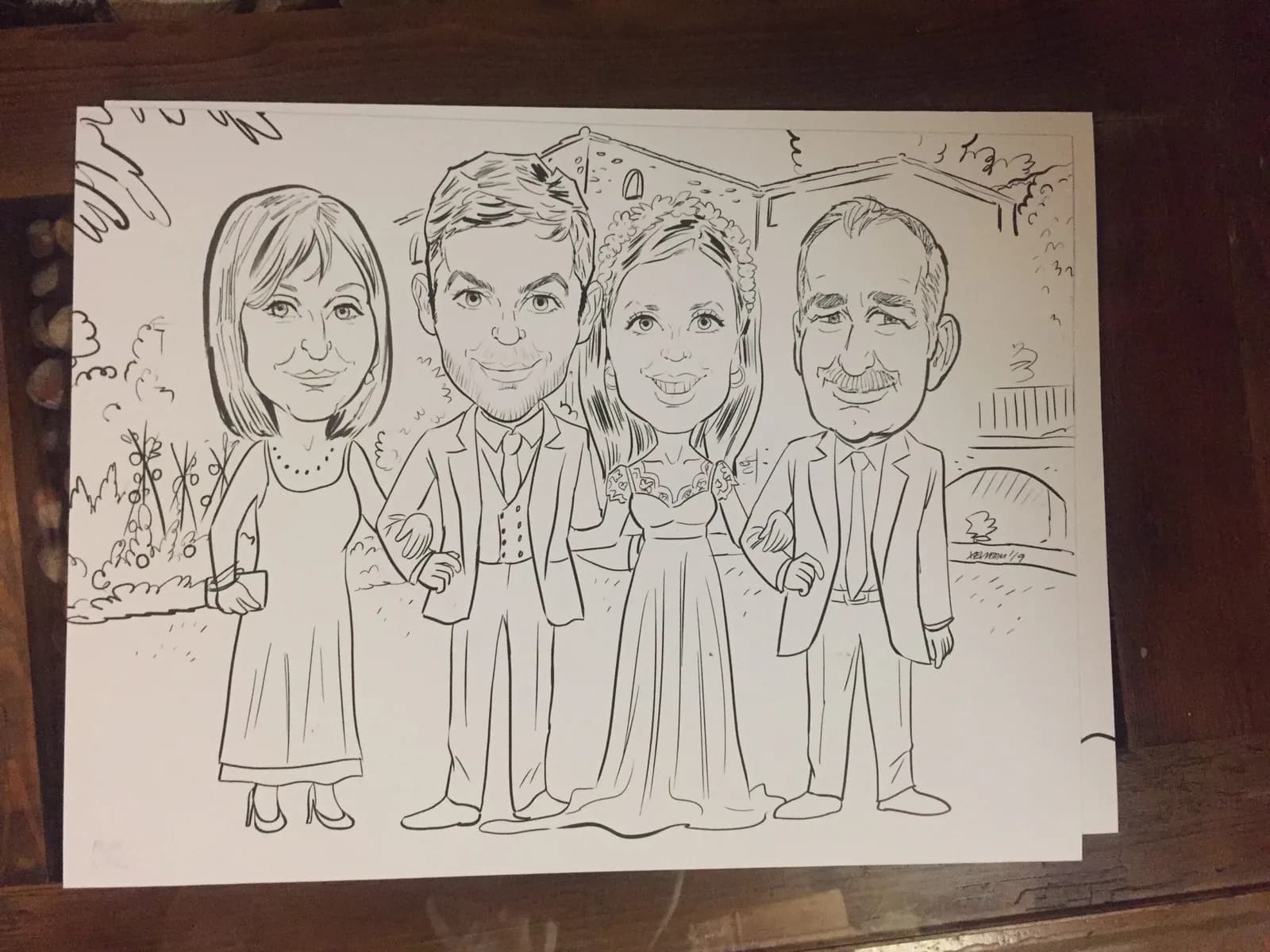 Caricatura en directe dels nuvis amb els pares, davant la masia